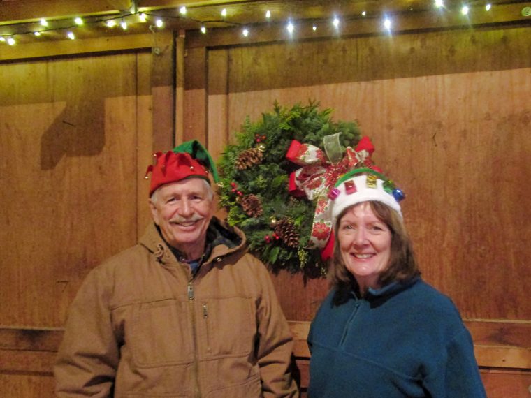 Ken and Libby Guthrie wearing holiday hats with their finished Christmas wreath
